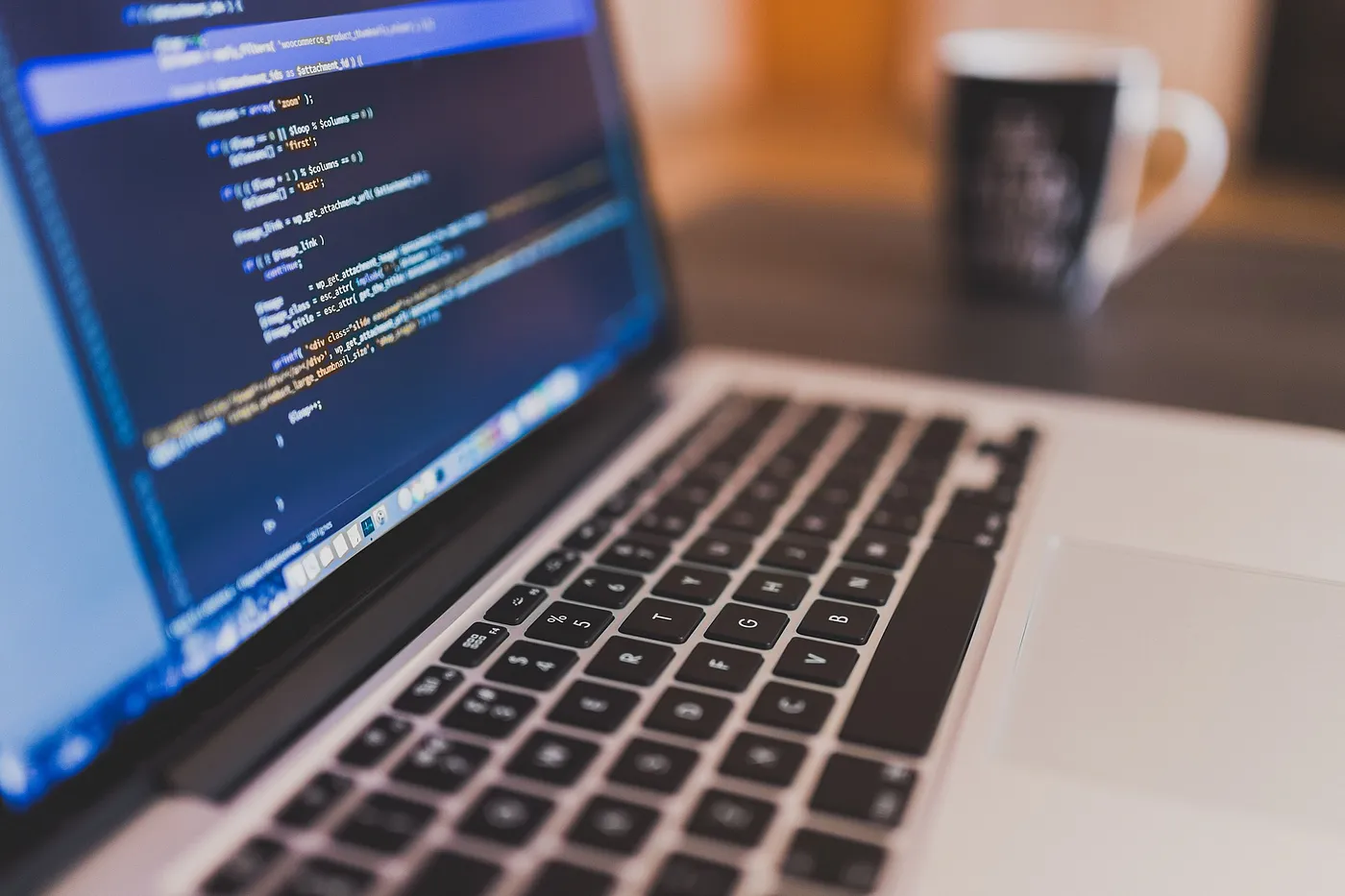 Laptop showing code with a coffee cup in the background